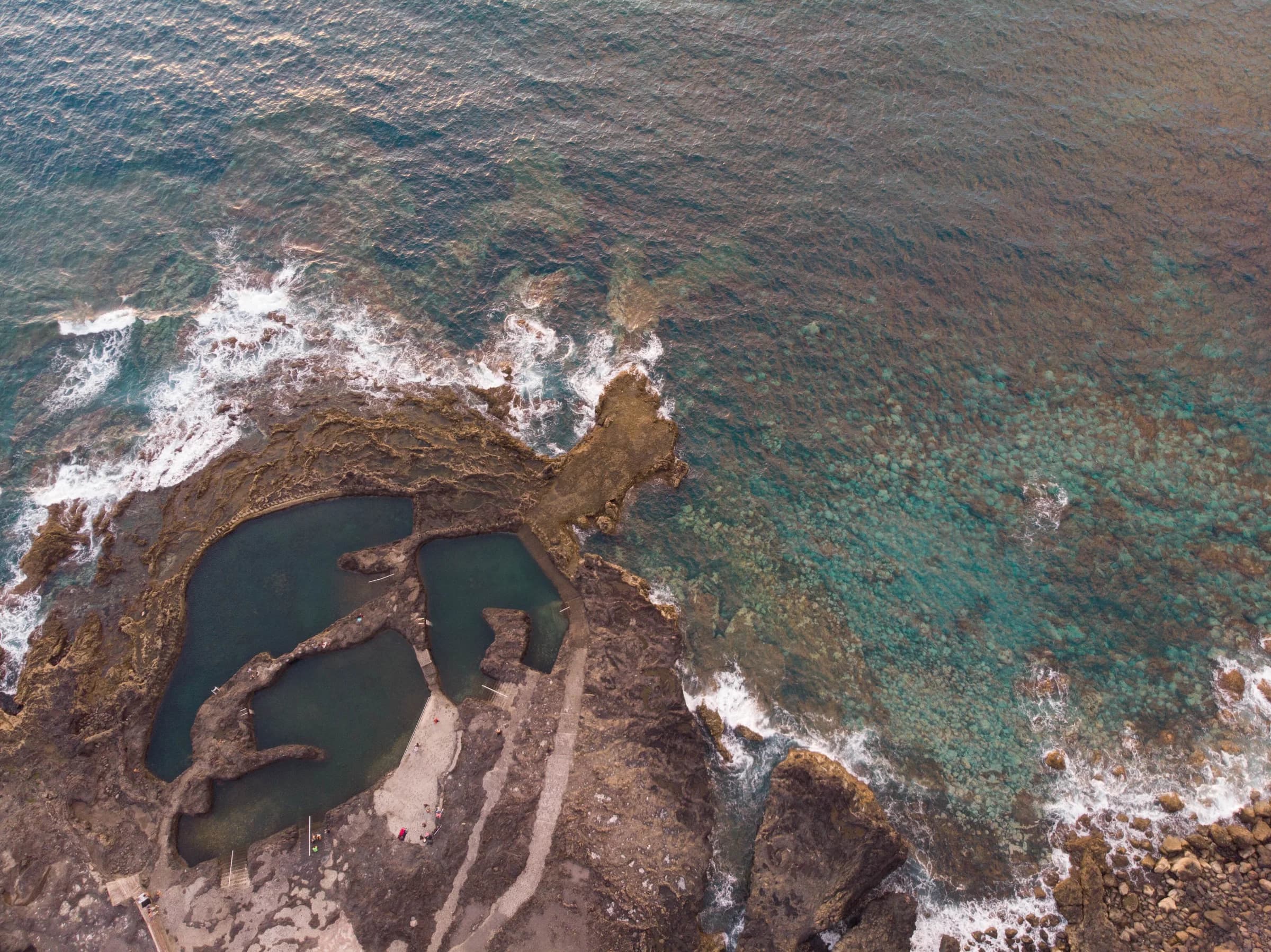 Aerial view of the Las Salinas natural pools in Agaete, sea pools in dark volcanic rock beside clear turquoise water